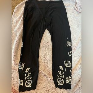 Athlete black leggings trimmed with silver floral trim and wavy bottom accent